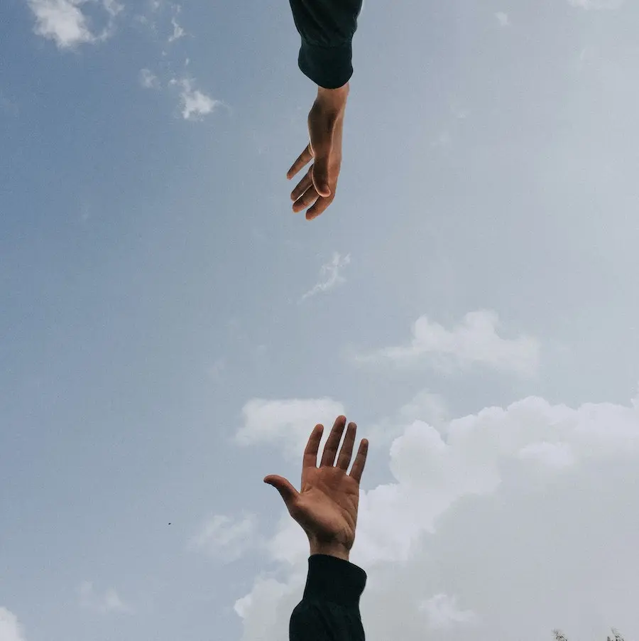 Two hands reaching out for each other across the sky
